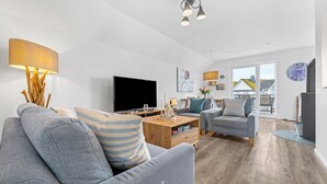 A modern living room with a sofa, armchair, coffee table, and TV.