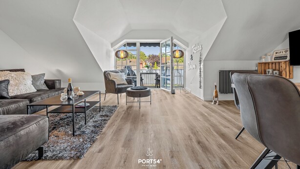 A spacious living room with a high ceiling, a large window, and a view of the outdoors. - Ferienwohnung Küstentiet - 2 balconies, 2 TVs, rural setting,by the sea, parking (Brodersby-Schönhagen)