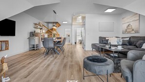 A modern living room with a dining area, a staircase, and a kitchen. - Ferienwohnung Küstentiet - 2 balconies, 2 TVs, rural setting,by the sea, parking (Brodersby-Schönhagen)