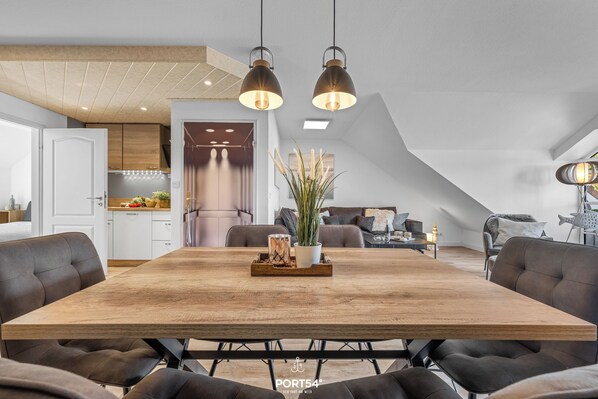 A modern dining area with a wooden table, black upholstered chairs, and pendant lighting.