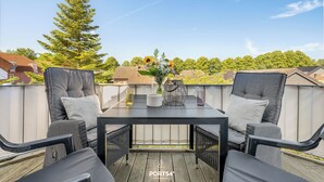 A rooftop patio with two chairs, a table, and a vase with flowers. - Ferienwohnung Küstentiet - 2 balconies, 2 TVs, rural setting,by the sea, parking (Brodersby-Schönhagen)