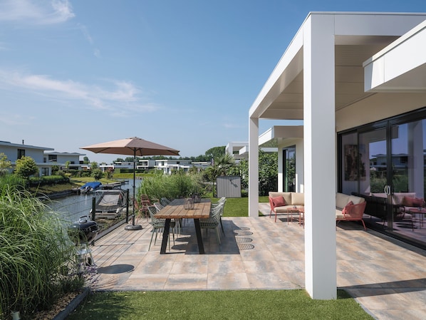Outdoor dining - Modern 8-person waterfront villa with fenced garden, private jetty, spacious open living area and full comfort for families – pets welcome. (Zeewolde)