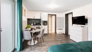 A modern apartment with a dining area, kitchen, and a TV.