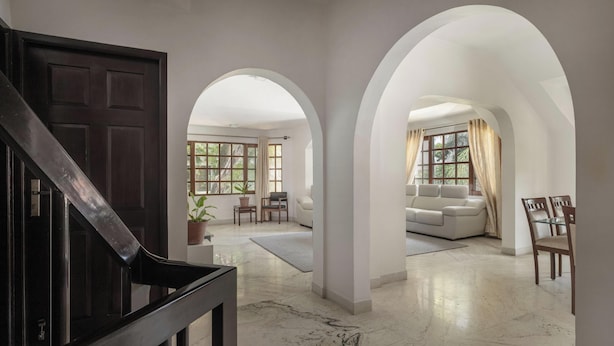 A spacious living area with a marble floor, a staircase, and a sofa set. - Casa Bianca by Red Olivenr Taj MG Roadpvt Garden (Bengaluru)