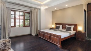A bedroom with a large bed, bedside tables, a ceiling fan, and a window with curtains. - Casa Bianca by Red Olivenr Taj MG Roadpvt Garden (Bengaluru)