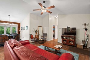 A spacious living room with a red leather sofa, wooden coffee table, and a ceiling fan.