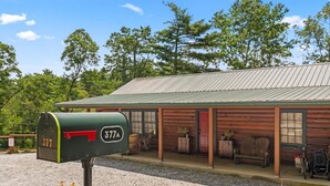 A wooden cabin with a metal roof, a porch with outdoor seating, and a mailbox labeled 377A. - Little Birds Nest (Highlands)