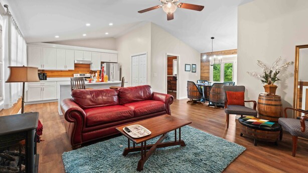 A spacious living area with a red leather sofa, wooden coffee table, and a ceiling fan. - Little Birds Nest (Highlands)