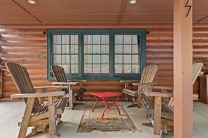 A log cabin interior with wooden chairs, a red bench, and a large window. - Little Birds Nest (Highlands)