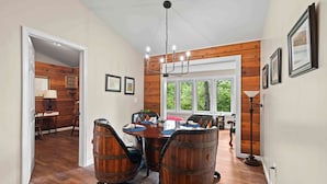 A dining area with a wooden table and chairs, a chandelier, and a view of the outdoors.