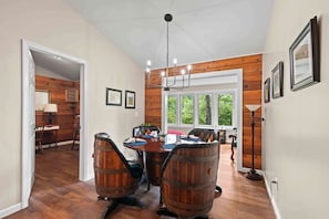 A dining area with a wooden table and chairs, a chandelier, and a view of the outdoors. - Little Birds Nest (Highlands)