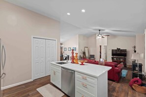A spacious living area with a kitchen island, a dining table, and a red sofa. - Little Birds Nest (Highlands)