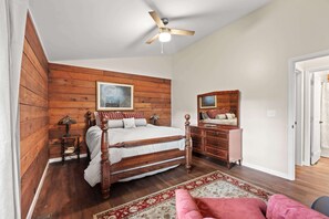 A bedroom with a wooden bed, a nightstand, a dresser, a ceiling fan, and a large mirror. - Little Birds Nest (Highlands)