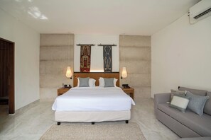 A modern bedroom with a large bed, a grey sofa, and two wall-mounted lamps. - Deo Villa Seminyak (Seminyak)