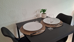A dining table with two chairs, a potted plant, and two wine glasses.