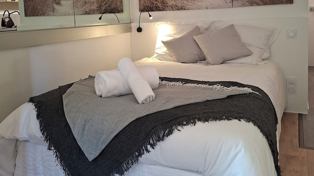 A bedroom with a bed, a large mirror, and a beach-themed artwork above the bed.