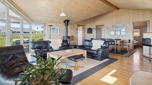 A spacious living area with leather sofas, a wooden coffee table, and a large window offering a view of the outdoors.