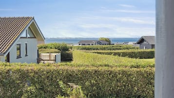 Une propriété située sur la côte, comprenant une grande maison, un petit abri de jardin et une haie bien entretenue.