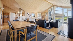 A spacious living area with a wooden ceiling, a dining table, and a sofa.