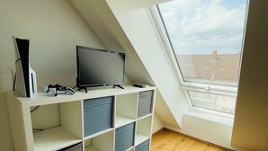 A modern room with a sloped ceiling, a built-in TV stand, and a skylight. - Vacation in the Franconian Lake District. Modern and light-flooded apartment. (Allersberg)