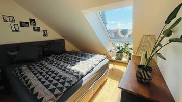 Un dormitorio con cama, tragaluz, planta en maceta y decoración en la pared.