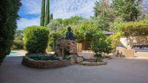Un jardin agrémenté d’une statue, d’une piscine et d’une construction en pierre.