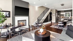 A modern living room with a fireplace, black and white striped rug, and a round coffee table with a vase. - New 1.5 Miles to Broadway | City Views | Game Room (Nashville)