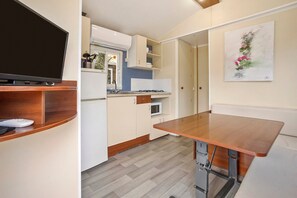 A modern kitchen with a TV, microwave, and wooden countertop.