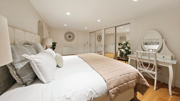 Un dormitorio con cama, mesita de noche, cómoda y espejo.
