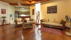 A spacious living room with hardwood floors, two sofas, a coffee table, and a large window. - Thai-Style Villa with Charm V114 (Kamala)