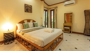 A bedroom with a wooden bed, a bedside table with a lamp, a wardrobe, and a large window with curtains. - Thai-Style Villa with Charm V114 (Kamala)