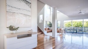 Un vaste espace de vie doté d’un plancher en bois, d’une console blanche et d’un escalier menant à un balcon.