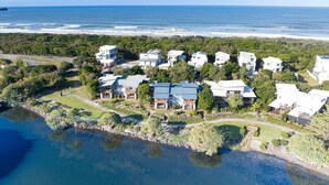 Vue aérienne d’une zone résidentielle côtière, avec des maisons, une plage et une étendue d’eau.