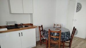 A kitchen with white cabinets, a wooden countertop, a sink, and a round dining table with chairs. - Renovated apartment in quiet wine-growing village. 15min from Auxerre. (Irancy)