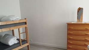 A bunk bed with a wooden frame and gray bedding, a wooden dresser with multiple drawers, and a light switch on the wall. - Renovated apartment in quiet wine-growing village. 15min from Auxerre. (Irancy)