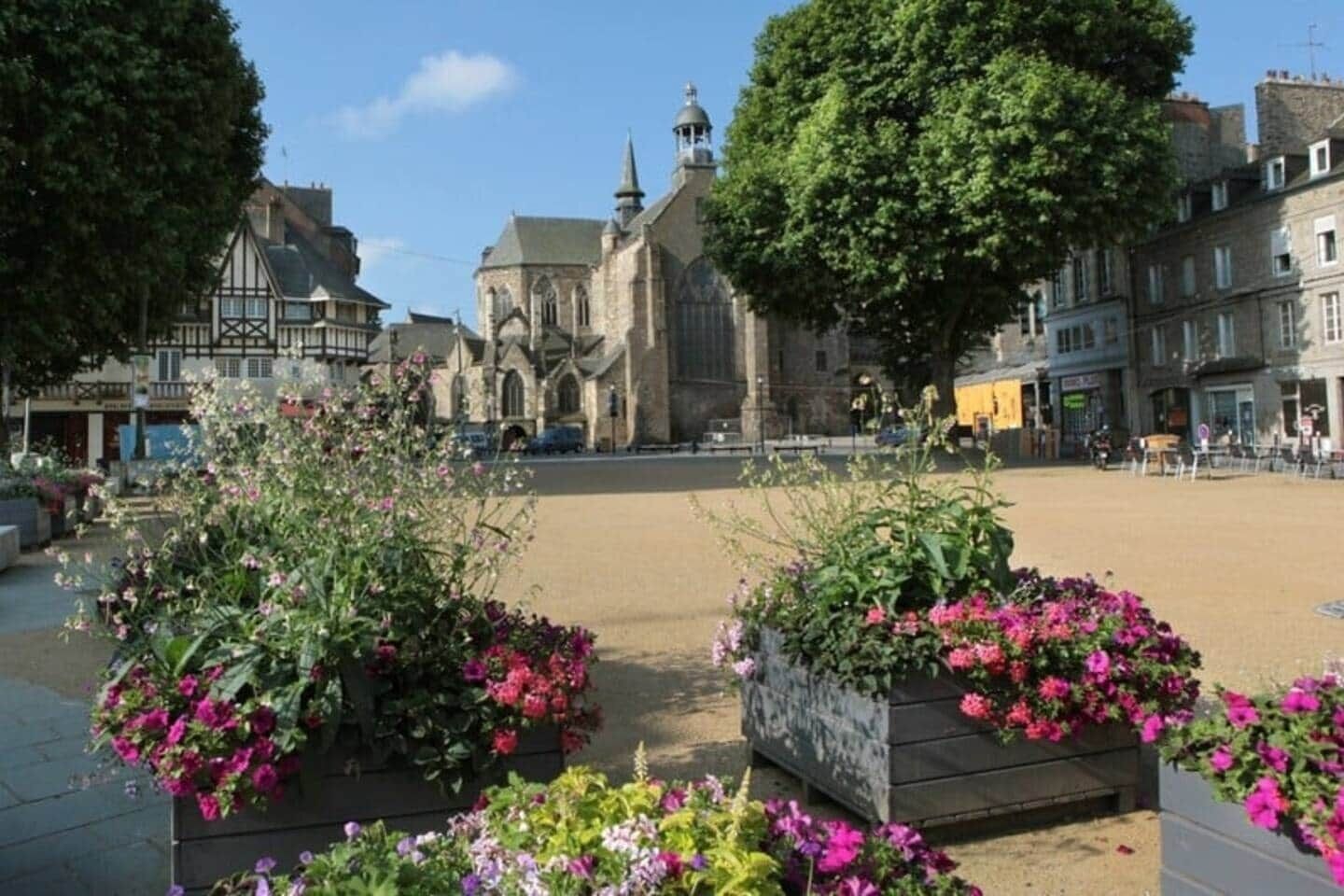 A town square with a historic church, flower planters, and traditional buildings.