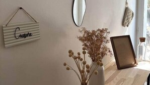 A wall with four oval mirrors, a hanging sign with the word "Cuisine," a vase with dried flowers, and a picture frame on a wooden tray. - La Parenthèse Douce (Saint-Brieuc)