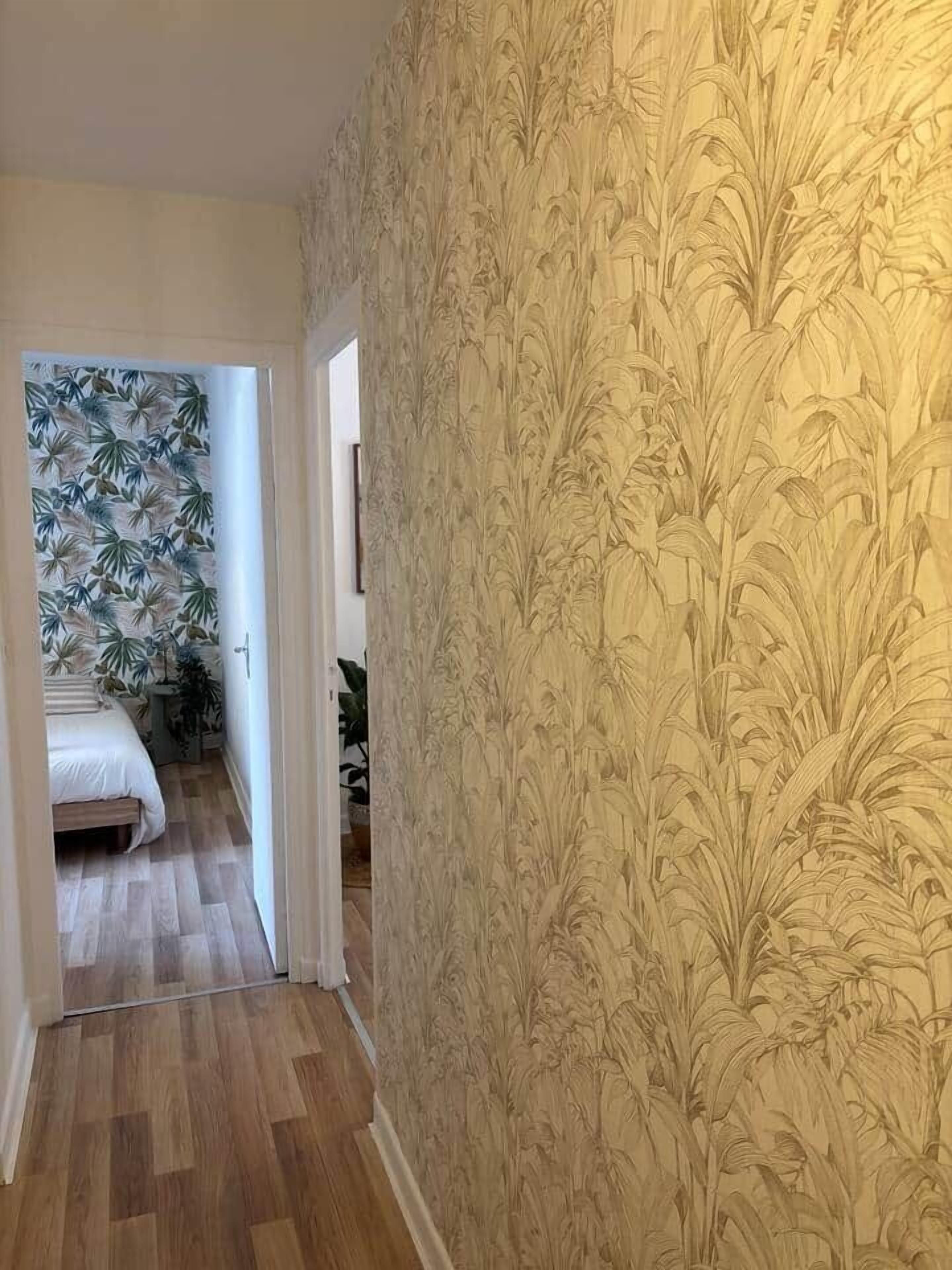 A hallway with a patterned wallpaper and a wooden floor.