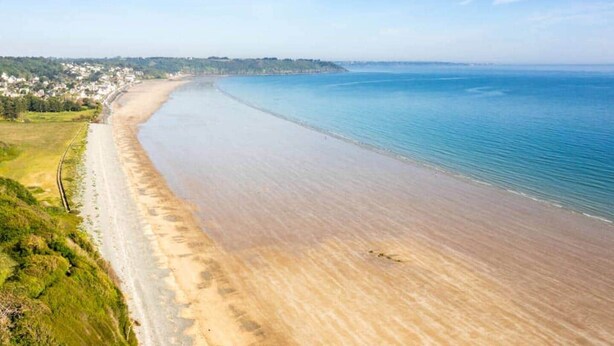 A coastal beach with a long stretch of sandy shore, a clear sky, and a distant town. - La Parenthèse Douce (Saint-Brieuc)