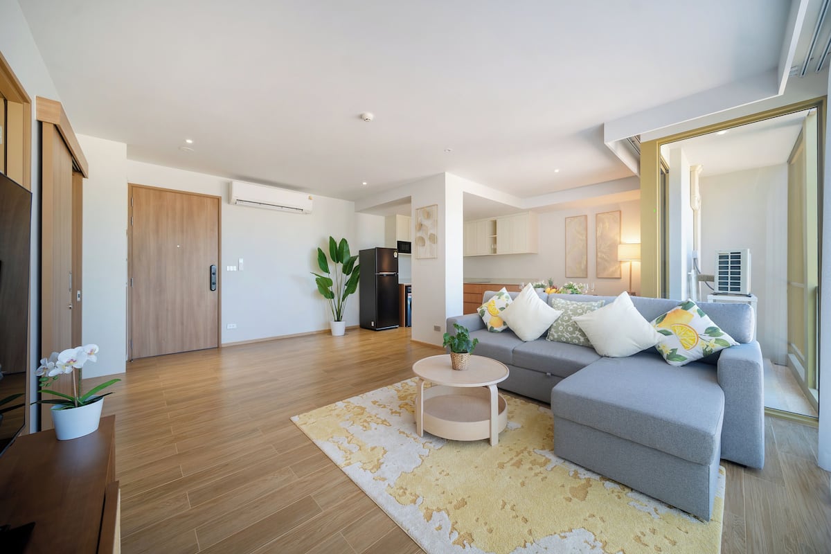 Un salon moderne avec un canapé gris, une petite table basse ronde et un plancher en bois.
