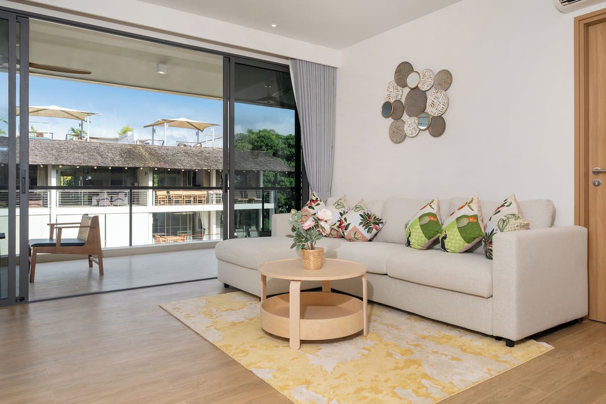 Un salon moderne avec un canapé, une table basse et une vue sur une terrasse extérieure.