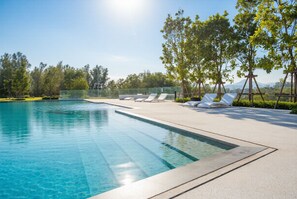 A swimming pool with clear blue water, surrounded by a paved deck with lounge chairs. - Laguna Beachside residences apartamens (Choeng Thale)