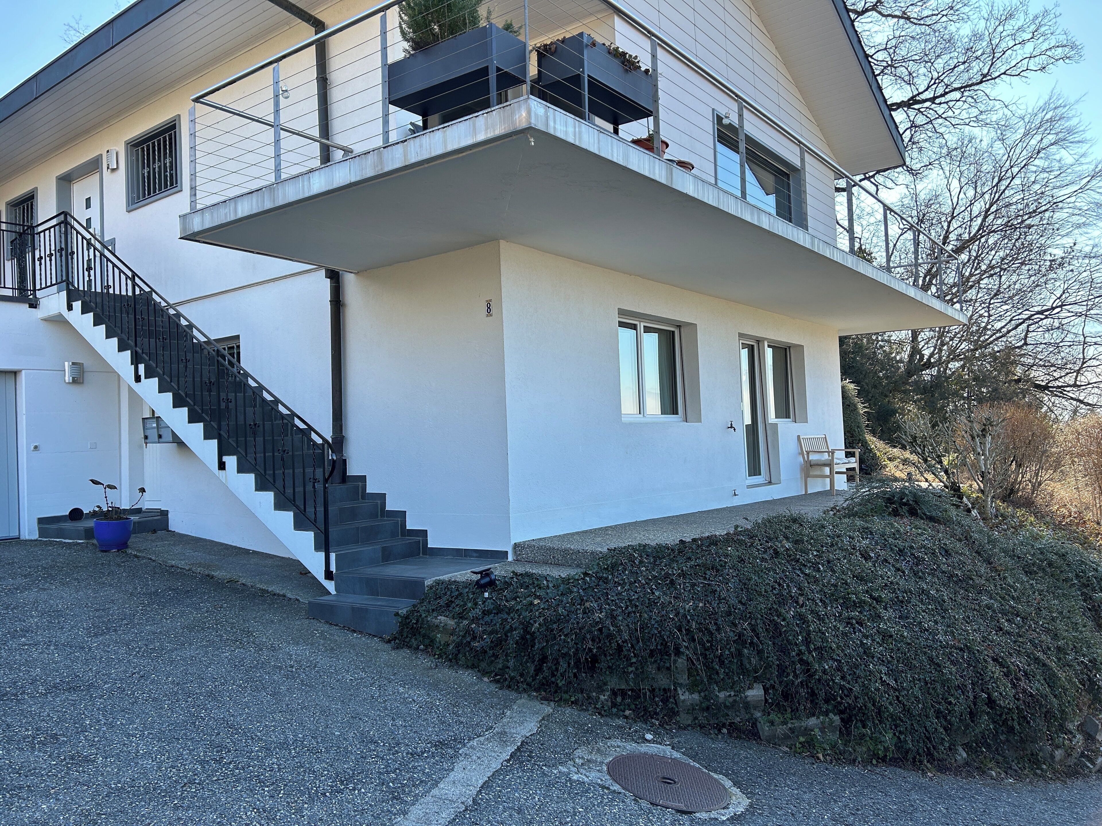 Une maison moderne à deux étages, avec un escalier menant à un balcon.