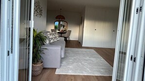 A modern living room with a sofa, a dining table, and a potted plant. - L'Appart Riviera panoramic view (Blonay - Saint-Légier)