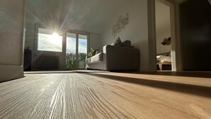 A room with a large window, a wooden floor, a sofa, and a bed. - L'Appart Riviera panoramic view (Blonay - Saint-Légier)