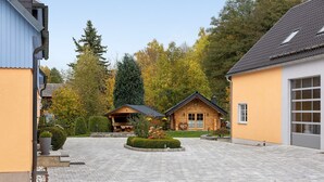 A courtyard with a paved walkway, wooden buildings, and a well-maintained lawn. - Teichmühle – Lakefront Apartment in Vogtland for Family & Pet-Friendly Holidays (Bad Brambach)