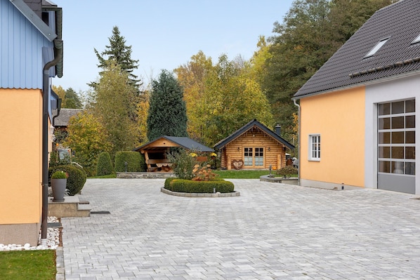 Une cour avec un chemin pavé, des bâtiments en bois et une pelouse bien entretenue.