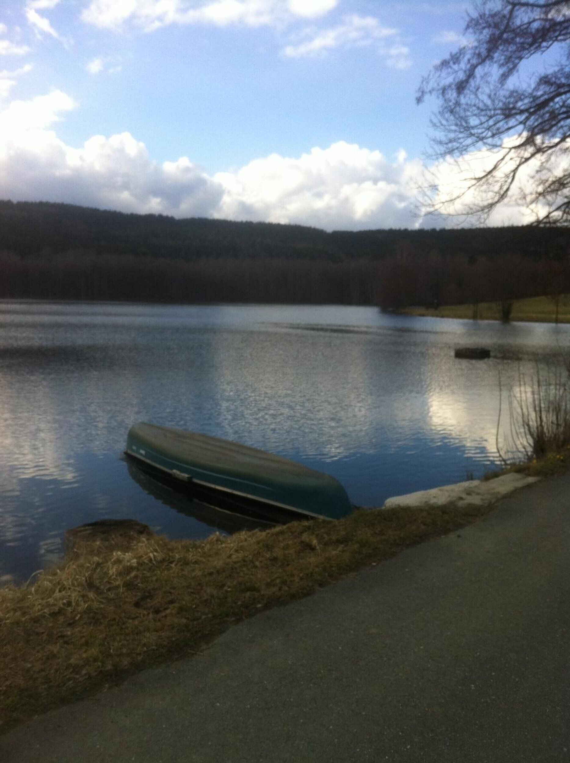 A calm lake with a dock and a path along the shore.