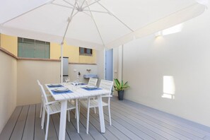A dining area with a white table set for four, a white umbrella, and a potted plant. - Torrigiani Charming Apartment (Firenze)