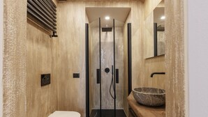Une salle de bain moderne avec une douche à parois de verre, un meuble-lavabo en bois doté d’un grand vasque et des toilettes.